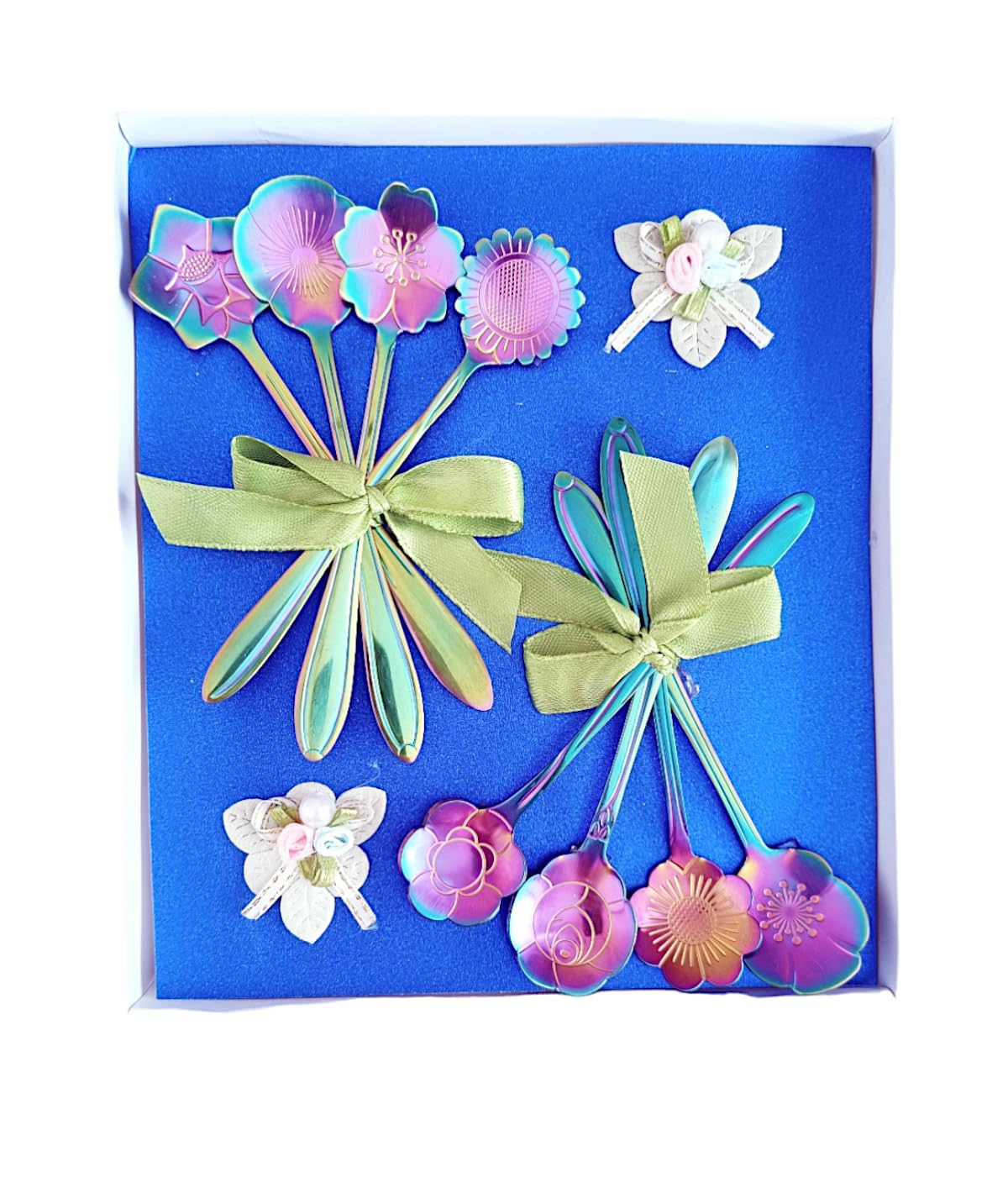 A blue gift box contains a set of iridescent spoons with floral designs, tied with green ribbons. The box also includes decorative floral and butterfly ornaments in soft pastel colours.